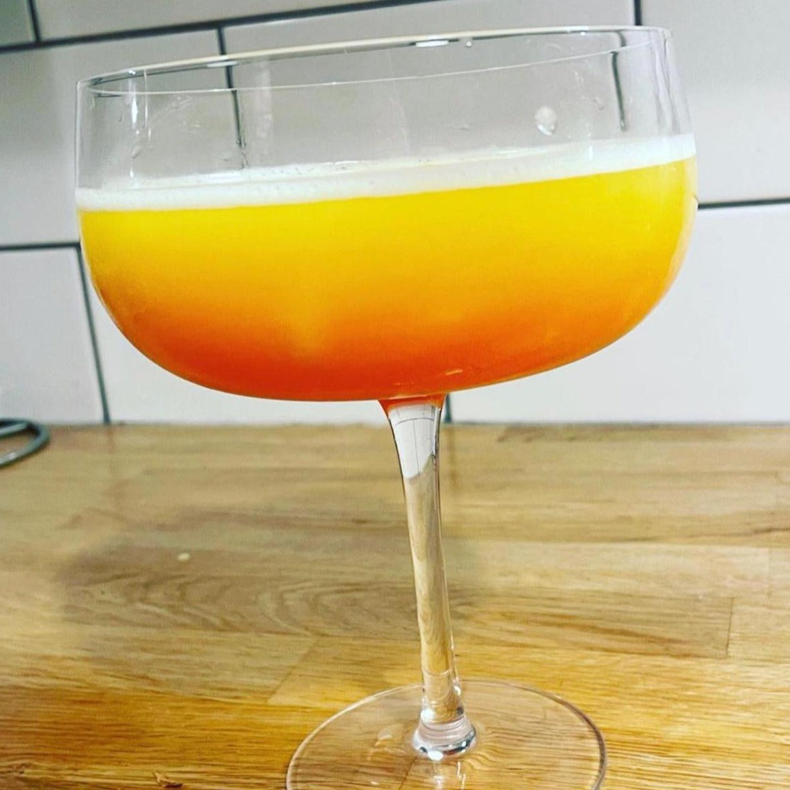A cocktail glass filled with a 'Dragoni' cocktail featuring Renegade Mango hot sauce