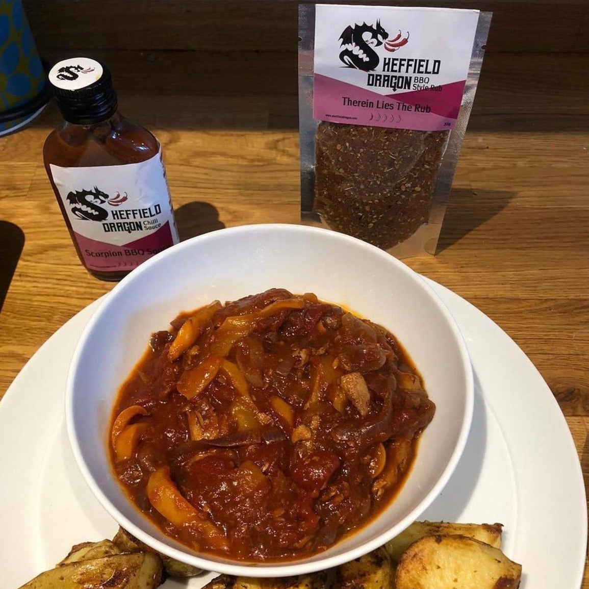 A picture of vegetarian BBQ ribs and potato wedges, featuring a packet of Scorpion BBQ sauce and 'Therein Lies The Rub'