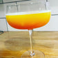 A cocktail glass filled with a 'Dragoni' cocktail featuring Renegade Mango hot sauce
