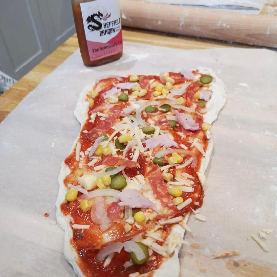 A picture of home made pizza drizzled with The Scorpion's Tale hot sauce