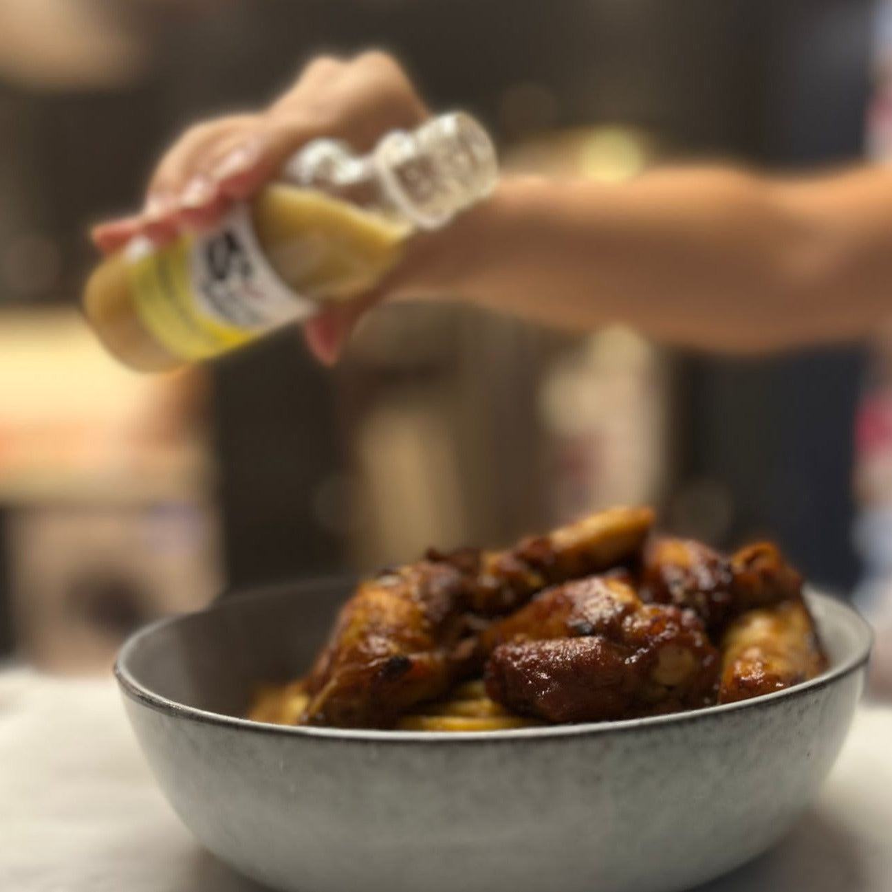 pouring yellow habanero hot sauce on chicken wings